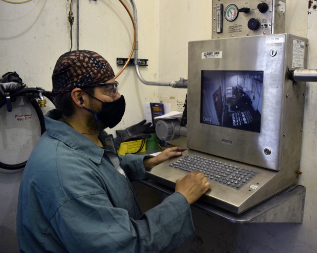 A Crane Army Ammunition Activity employee monitors a robotic arm as it loads munitions into the lathe as part of an ammunition demilitarization process, reducing obsolete munitions in storage and freeing up space for future munitions. Crane Army...