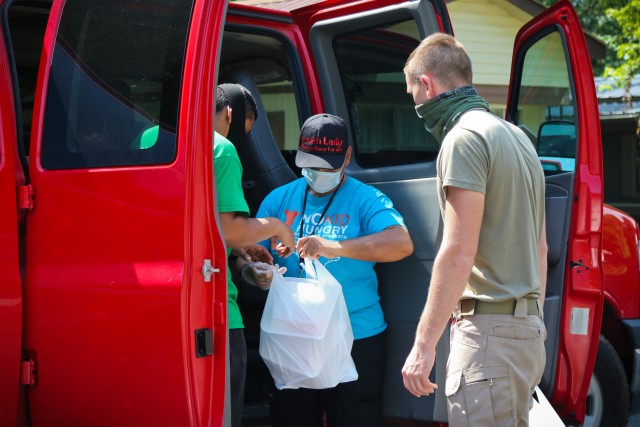 North Carolina Army National Guard Spc. Acevedo Enrique (left) and Pvt. 1st Class Bennie Kinley (right), both assigned to the 875th Engineer Company, work with Amelia Lozano, a school cafeteria worker, to distribute breakfast meals, prepared at...