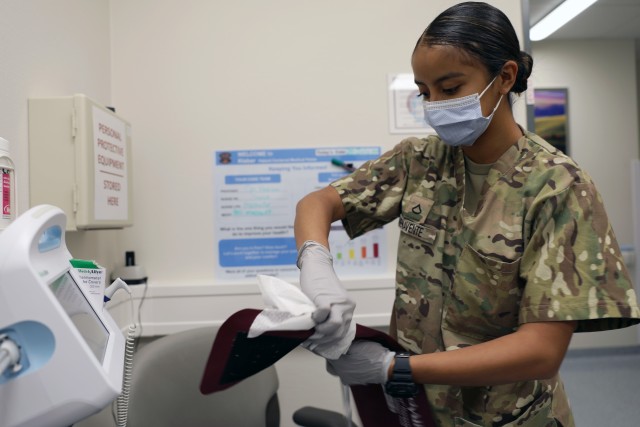 Pfc. Destiny Buenavente, a combat medic specialist assigned to Kleber Army Health Clinic, disinfects a blood pressure monitor following a patient's medical examination.