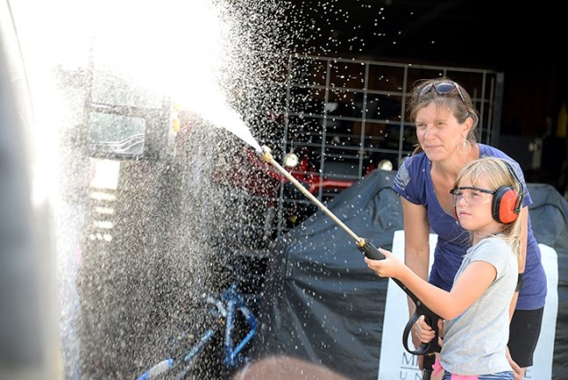 Eight-year-old Angelina VanKirk uses a power washer to rinse the side of her neighbor's vehicle while her mother, Theresa VanKirk, monitors July 25 on post. The neighbor offered to pay the Isabella and her twin sister, Isabella, to wash the vehicle, and the girls said they were going to use the money toward a Lego playset. The Fort Leavenworth Lamp staff provided a glimpse of life on post Saturday on the same day that "Life in a Day" participants were filming glimpses of their lives for the worldwide documentary July 25. Photo by Prudence Siebert/Fort Leavenworth Lamp
