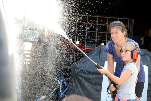 Eight-year-old Angelina VanKirk uses a power washer to rinse the side of her neighbor's vehicle while her mother, Theresa VanKirk, monitors July 25 on post. The neighbor offered to pay the Isabella and her twin sister, Isabella, to wash the...