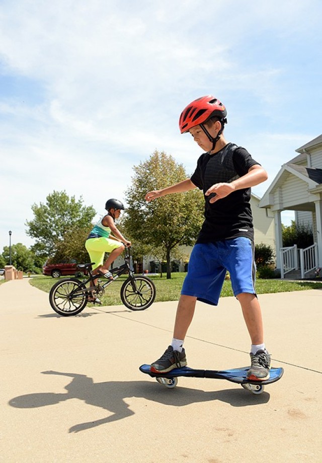 Ten-year-old Stephen Redmon gets comfortable on a casterboard while his neighbor, 9-year-old Luca Brown, rides his bike around the driveway July 25 on post. Stephen said it was his first time on the RipStik, but that he had skateboarded before so it wasn't difficult to learn. The Fort Leavenworth Lamp staff provided a glimpse of life on post Saturday on the same day that "Life in a Day" participants were filming glimpses of their lives for the worldwide documentary July 25. Photo by Prudence Siebert/Fort Leavenworth Lamp