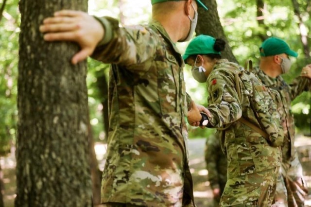 Warrant officer candidates of class 20-002 shuffle across a thin board between trees while keeping everyone stable during a team building obstacle course at the Kansas Regional Training Center in Salina, Kansas, June 26, 2020. The Warrant Officer...