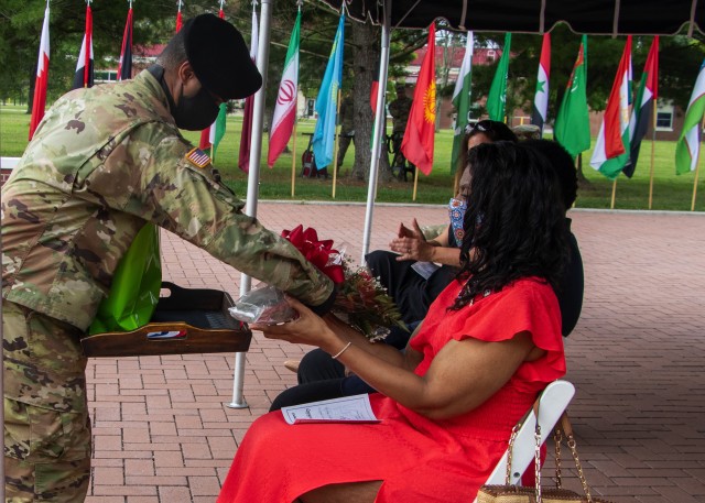 Staff Sgt. Jamal Crosby, 1st Theater Sustainment Command, presents a bouquet of red roses to Mrs. Veronica Smalls, wife of outgoing Command Sgt. Maj. Bernard P. Smalls Sr., as a symbol of the command’s deep respect and admiration during the twenty months with the command, during the 1st TSC’s change of responsibility ceremony held at Fort Knox, Kentucky, July 28 2020. (U.S. Army photo by Spc. Zoran Raduka, 1st TSC, Public Affairs)