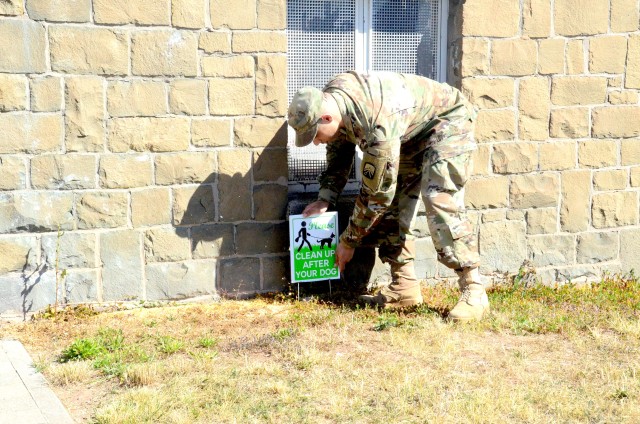 Sgt. Marion Kirkland, Baumholder Army Family Housing building coordinator, places a sign next to the housing building he's responsible for, to alert residents to pick up after their pets.