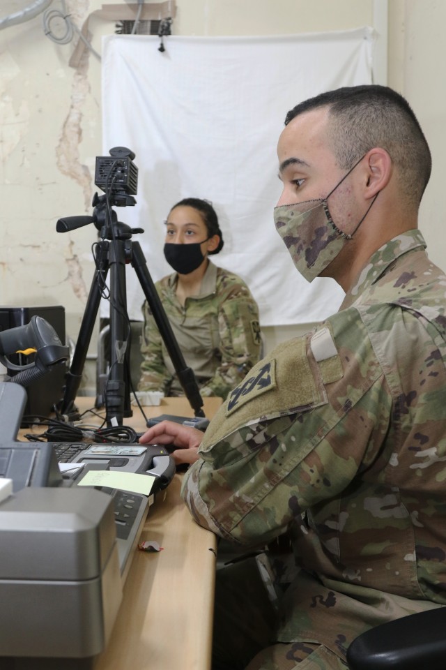 U.S. Army Sgt. Kelvin M. SanchezRivera, 207th Regional Support Group human resources NCO, helps 1st Lt. Jennifer Polanco, 2nd Battalion, 43rd Air Defense Artillery Regiment communications officer, with her identification card July 10, 2020 at...