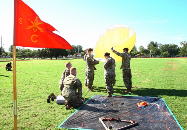 The guidon for C Battery, 5th Battalion, 5th Air Defense Artillery, flutters in a strong wind during launch preparations of a helium balloon July 31, 2020, at the Dr. Charles E. Green Field near Lawton High School. Instruments carried aloft by the...