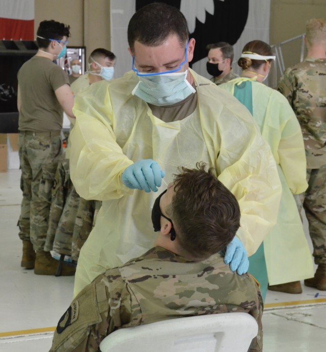 Approximately 4,000 Soldiers assigned to 2nd Brigade Combat Team, 101st Airborne Division (Air Assault), were tested for COVID-19 last week at Hanger 3 on Campbell Army Airfield in preparation for their rotation at the Joint Readiness Training Center-Fort Polk, Louisiana. In each testing lane, medics in full personal protective equipment conduct each swabbing. A swab, which are Q-tips on long sticks, is pushed up into the nasal cavity for 10 seconds to collect the sample. (U.S> Army photo by Emily LaForme, Fort Campbell Courier)