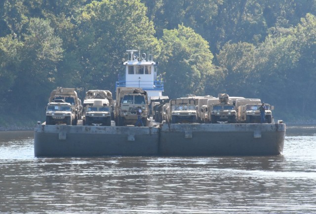 A barge pushing a deck carrying vehicles assigned to the 2nd Brigade Combat Team, 10th Airborne Division (Air Assault), moves into place at the Central Louisiana Regional Port in Alexandria, La. Aug. 3. The vehicles were off-loaded and then...