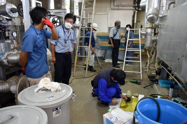 A contractor, front right, begins repairing an air conditioner in Building 1050 at Camp Zama, Japan, Aug. 6.