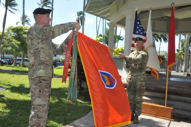 The 311th Signal Command (Theater) Commanding General, Brig. Gen. Jan C. Norris, left, and Command Sgt. Maj. Randy Gillespie, place an Army Superior Unit Award streamer during a presentation ceremony at the historic Palm Circle Gazebo on Fort Shafter, Friday July 24, 2020. (Official U.S. Army Photo by Spc. Bishnu Bhandari)
