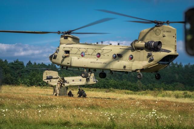CH-47 Chinooks from B Co "Big Windy," 1-214th General Support Aviation Battalion hover low while paratroopers from the 173rd Airborne Brigade  hook their pallet of equipment to the underside of the helicopters. (U.S. Army photo by Maj. Robert Fellingham)