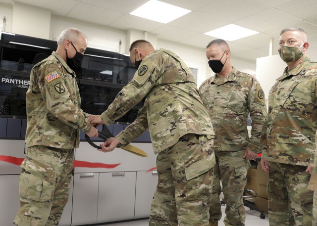 Brig. Gen. Mark Thompson (right), commanding general, Regional Health Command Europe, and Command Sgt. Maj. Kyle Brunell, command sergeant major, RHCE, cut a ribbon to introduce Landstuhl Regional Medical Center’s first high-throughput testing system for COVID-19, July 8.