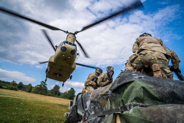 A CH-47 Chinook from B Co "Big Windy," 1-214th General Support Aviation Battalion moves into position directly over a pallet of equipment while paratroopers from the 173rd Airborne Brigade prepare to hook it to the underside of the helicopter. (U.S. Army photo by Maj. Robert Fellingham)