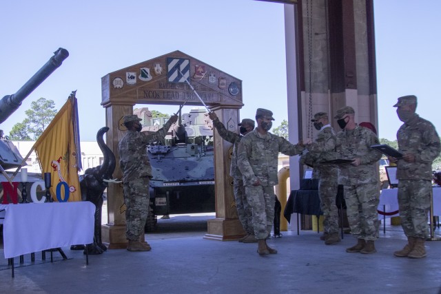 Soldiers pass under the noncommissioned officer arch way, as part of their passage into the corps of NCOs during an NCO induction ceremony, Aug. 5 on Fort Stewart. The Desert Rogues, 1st Battalion, 64th Armored Regiment, 1st Armored Brigade Combat Team, held an induction ceremony for 53 new NCOs. The ceremony is a time-honored tradition for Soldiers who earn chevrons. (U.S. Army photo by Spc. William Griffen)