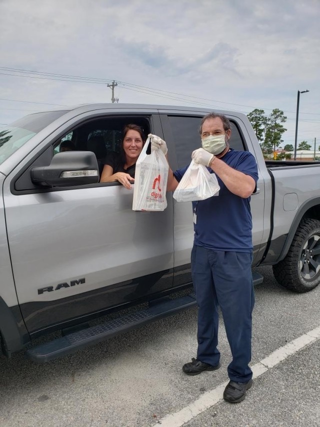 Andrew Sohlstrom, a library technician at George P. Hays Library, delivers a curbside order to Crystal Constable, a military Family member, Aug. 11 at the library parking lot on Fort Stewart. (Courtesy photo)