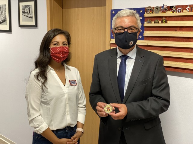 Adriana Fink, Baumholder USO center operations manager, stands with Rheinland-Pfalz Minister of the Interior Roger Lewentz as he presents a coin from his state. The minister toured the USO in Baumholder for about 20 minutes and placed the coin with others presented to the USO.