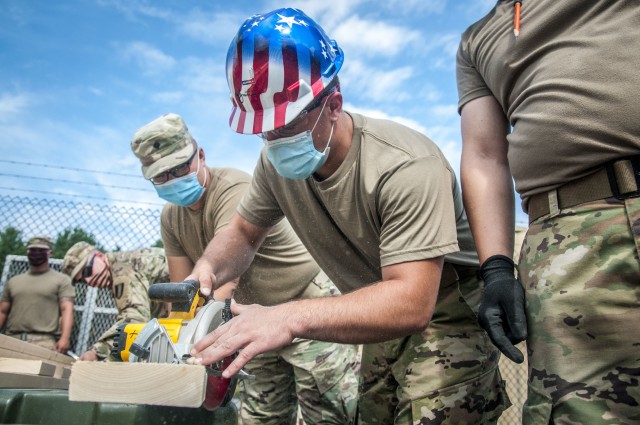 TAUNTON, Mass. – Soldiers assigned to the 338th Engineer Company cut planks of wood in preparation to construct a gazebo at the Army Reserve Center, here, Aug. 13, 2020. This construction project will help provide a shaded area for Soldiers to take breaks while working in the motor pool.