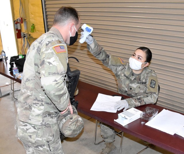 Spc. Stephanie Rivera, 32nd Hospital Center, Fort Polk, checks the temperature of an inprocessing 2nd Brigade Combat Team, 101st Airborne Division (Air Assault) Soldier in JRTC Ops Gp’s North Fort Polk clam shell Aug. 12.