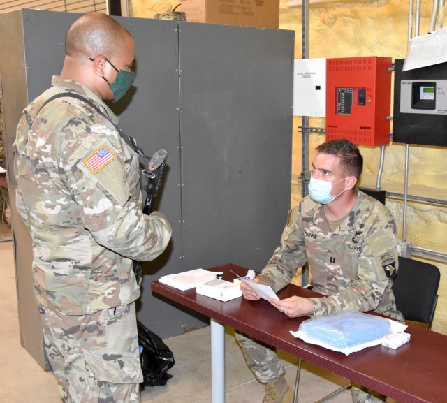 Capt. Brent Turpin, 2nd Brigade Combat Team, 101st Airborne Division head nurse (seated), conducts a COVID-19 screening on one of the unit’s Soldiers after he arrived at North Fort Polk Aug. 12.
