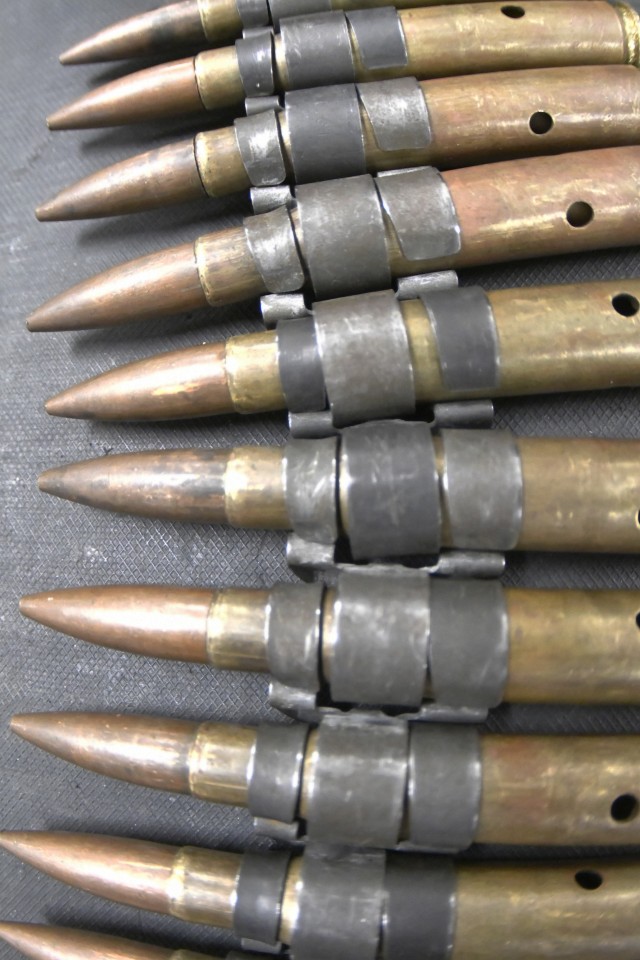 Dummy rounds for the .50 caliber heavy machine gun rest on a classroom table. The rounds are used to teach students in the 94T Short Range Air Defense System Repairer Course how the weapon operates.