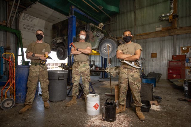 Volunteer mechanics of KFOR 27 RC-E (from left to right) Spc. Andrew Gross, Sgt. Jason Bergstad and Sgt. Nicholas Vestal pause working on an M998 HMMWV Front Main Seal,  at the contractor shop in Camp Bondsteel, Kosovo Aug. 12. (U.S. Army National Guard photo by Maj. W. Chris Clyne)
