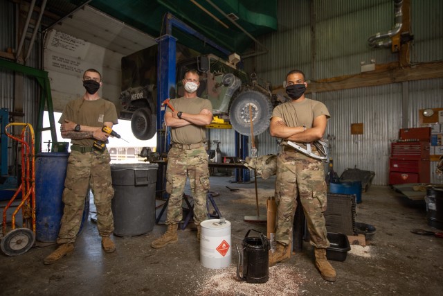 Volunteer mechanics of KFOR 27 RC-E (from left to right) Spc. Andrew Gross, Sgt. Jason Bergstad and Sgt. Nicholas Vestal pause working on an M998 HMMWV Front Main Seal,  at the contractor shop in Camp Bondsteel, Kosovo Aug. 12. (U.S. Army National...
