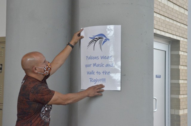 Alberto Gonzalez, security specialist for Fort Campbell High School, hangs posters, Aug. 18, reminding students and staff to social distance in preparation for Aug. 24, the first day of school. (Emily Laforme, Fort Campbell Courier)