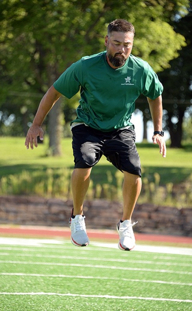 Jason Fullen, Youth Sports and Fitness assistant director, performs exercises to increase leg strength while making  a fitness video Aug. 18 at Normandy Field. The Youth Sports and Fitness team has been producing fitness videos for Facebook over the past several months to keep area youth and families exercising on their own since organized sports were put on hold due to COVID-19 precautions. Photo by Prudence Siebert/Fort Leavenworth Lamp