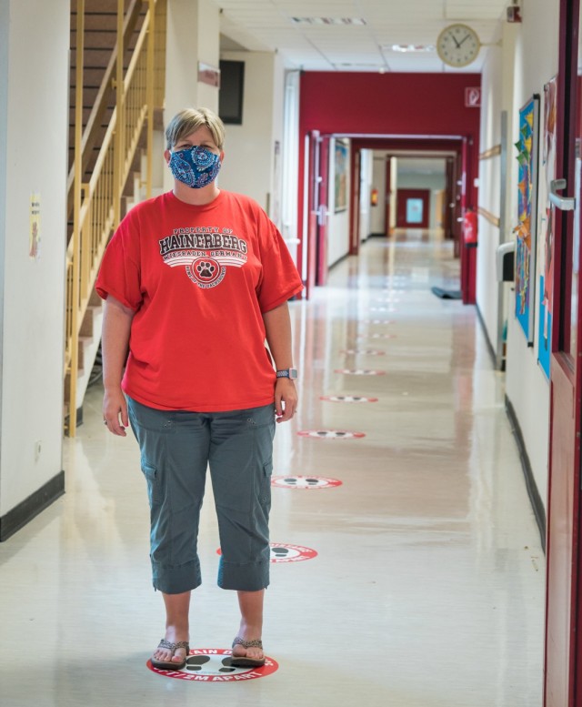 WIESBADEN, Germany – Dr. Tonya Laliberte demonstrates how students at Hainerberg Elementary School will utilize markings around the school to encourage physical distancing Aug. 13, 2020. Students will have to wear masks if they can’t maintain the proper distance, as marked by floor decals inside the school, painted dog mascots along the exterior entrances and exercise icons in the recess area.