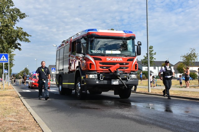 WIESBADEN, Germany - A fire and rescue vehicle, flanked by first responders, drives along Via Principalis during a First Responders Day parade Aug. 21 on Clay Kaserne.