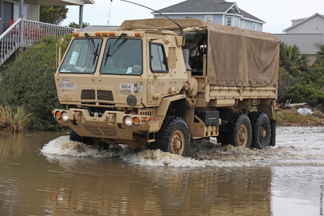 Vehicles assigned to the 878th Engineer Vertical Construction Company, 105th Engineer Battalion, drive through flooded roads and debris on the way to assist stranded civilians on Oak Island, N.C., Aug. 5, 2020. The North Carolina National Guard deployed teams across the Eastern portion of the state to assist civilians and North Carolina Emergency Management with damage inflicted by Hurricane Isaias. 