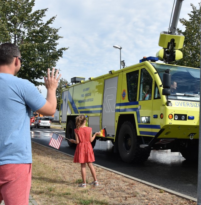 WIESBADEN, Germany - Family members wave as a fire rescue vehicle from U.S. Army Garrison Wiesbaden drives by during a First Responders Day parade Aug. 21 on Clay Kaserne.