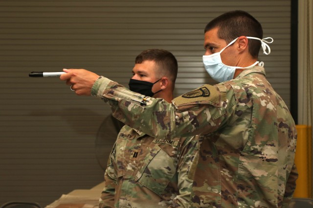 Maj. Matthew Hygema, S2 OIC, 54th Security Forces Assistance Brigade, explains the tactical operations center layout to Cpt. Jacob Kegle, 157th IN BDE Military Intelligence OC/T, during the 54th SFAB’s second annual training event at Camp Atterbury, IN, August 12, 2020.  (U.S. Army photo by Sgt. James Hobbs)