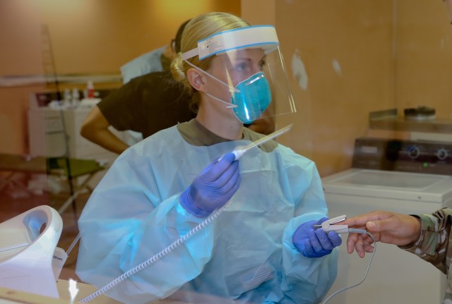 Sgt. Emily Dwyer, a licensed practical nurse with 14th Combat Support Hospital and the medical team NCOIC at the Fort Benning Recovery Center, checks the oxygen levels of a Soldier in the isolation camp. 
...
