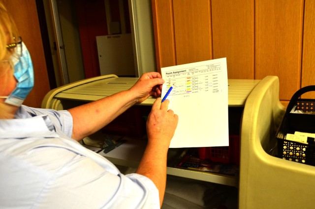 A Baumholder Lagerhof lodging facility housecleaning staff member checks her list of occupied rooms color-coded by quarantined, non-quarantined and checked out customers.