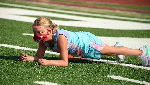 Six-year-old Addilyn Banter holds a plank for 10 seconds during Fitness Camp Aug. 24 at Normandy Field. Camp participants learned how to properly perform bodyweight and core exercises, and took frequent water and mask breaks. Photo by Prudence...