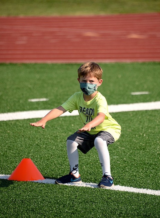 Six-year-old Liam Caffery watches Youth Sports and Fitness staff as he practices proper form for an air squat during Fitness Camp Aug. 24 at Normandy Field. Photo by Prudence Siebert/Fort Leavenworth Lamp