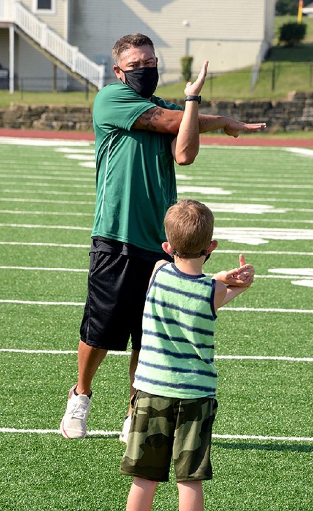 Jason Fullen, Youth Sports and Fitness assistant director, leads 5-year-old Chris Farrington in cool-down stretches at the end of the first session of Fitness Camp Aug. 24 at Normandy Field. Photo by Prudence Siebert/Fort Leavenworth Lamp