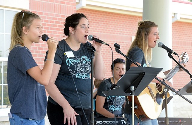 Fifteen-year-old Kiley Atkins; Caitlyn Mair, praise and worship leader for Protestant Women of the Chapel; Kayla Atkins; and Ashley Saulnier on keyboard perform a medley of "This Is the Day" and "Rise and Shine" during the PWOC drive-in fall...