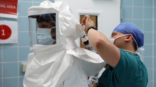 Maj. (Dr.) Neel Shah, an anesthesiologist at Landstuhl Regional Medical Center, gets assistance with putting on a powered air-purifying respirator.