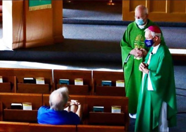 Bishop Richard Spencer (in red cap) and Father Robert Cook speak to a Fort McCoy community member July 19 at the Catholic Chapel. Spencer visited the Fort McCoy RSO to meet and talk with leadership about the religious community and services...