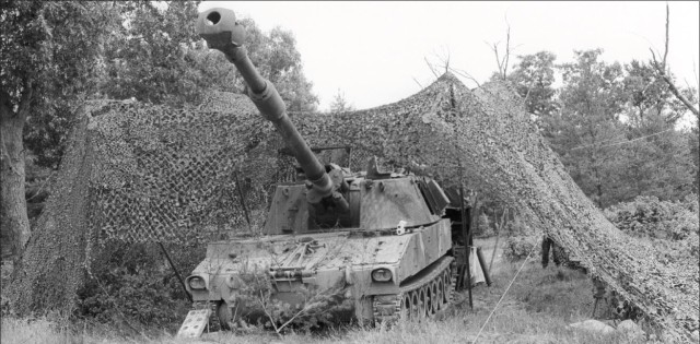 An Army tracked vehicle is hidden under camouflage netting during training in 1984 at Camp McCoy, Wis. (U.S. Army file photo)