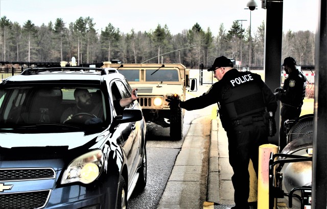 Police officers with the Directorate of Emergency Services Police Department check identification cards April 3, 2020, at the Main Gate at Fort McCoy, Wis. At that time, it was still early in the installation’s response to the national COVID-19...
