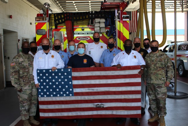 As a way to say thank you for your support, members of the Forest Glen Fire Department proudly present the Garrison command team with a US flag made of engine fire hoses that have reached their lifecycle. Pictured from left to right: Garrison...