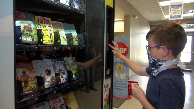 Jameson Faust makes a selection from a new book vending machine at Gen. Myer Elementary  at Fort Huachuca, Ariz. Robert Faust Jameson’s father designed the art wrap that covers the machine.