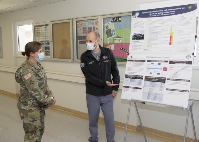 (From left) Col. Jana Nohrenberg, chief nursing officer, Landstuhl Regional Medical Center, discusses a poster presentation with Jeffrey Bauman, a registered nurse at LRMC's Medical / Surgical Ward, during a Best Practices Showcase at LRMC, Aug. 6. The showcase kicked off LRMC's annual Nurse Medic Tech Week, held Aug. 6-12, in lieu of the tradition May celebration due to restrictions from COVID-19.