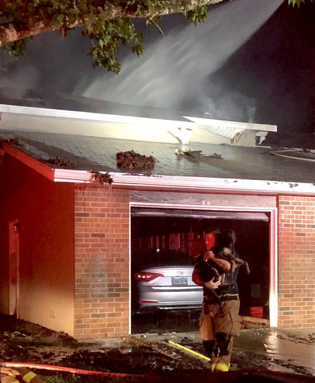 A Fort Polk DES firefighter rescues a pet dog, Buck, from a house fire on Fort Polk Sept. 7.