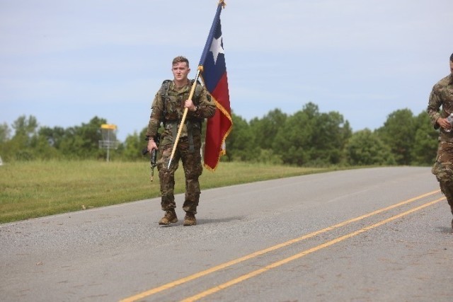 Specialist Jacob Arndt, Texas Army National Guard, carries the Texas State Flag the last half mile of the twelve-mile ruck march during phase two of the 2020 Region V Best Warrior Competition at Camp Robinson, Ark.