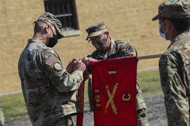 Capt. Joseph Kinsey, left, and 1st Sgt. Wesley Poell, center, the former commander and first sergeant of Battery C, 1st Battalion, 161st Field Artillery Regiment, 130th Field Artillery Brigade, attach the Hamilton Award streamer to the unit guidon at a ceremony in Newton, Kansas, Sept. 12. where the unit was recognized as the best field artillery unit in the Army National Guard for 2019.